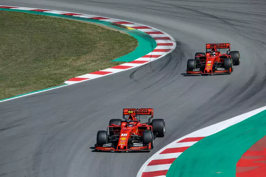 Ferrari Formula 1 cars driving thru a chicane